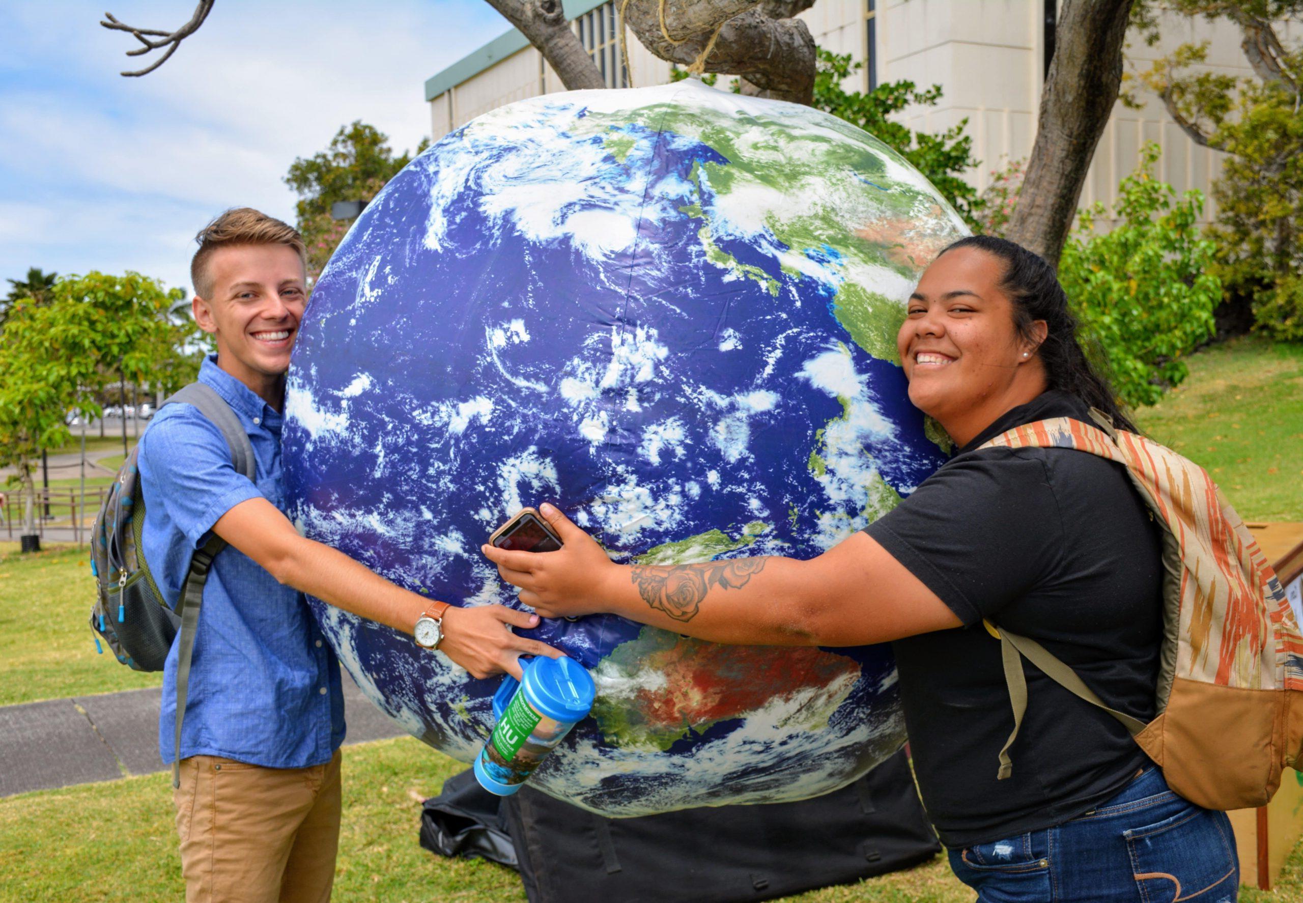 两个学生抱着一个充气地球仪